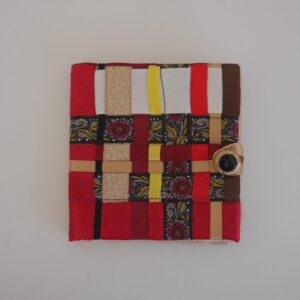 A multicoloured needle case made from assorted ribbons woven together