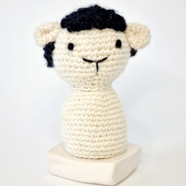 Cream and black crochet sheep egg cosy sat on an egg cup