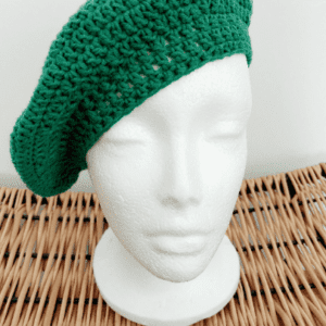 Crochet beret hat using 100% cotton yarn, displayed on a white mannequin head on small wicker stool.