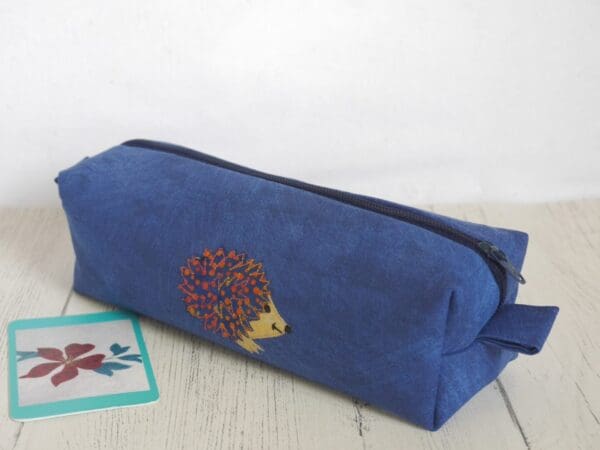 Box style pencil case with zipped top and appliqued hedgehog on friont.