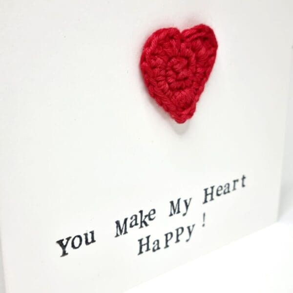 A close up view of a white card with a red heart on the front and the words 'you make my heart happy'