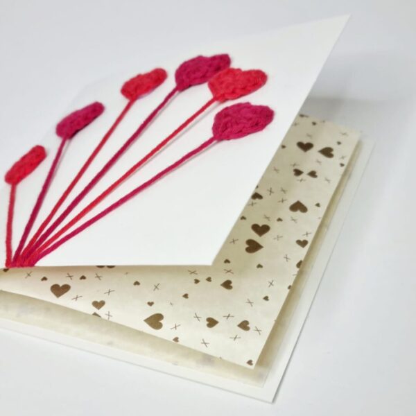 A square greetings card with red love hearts on the front and gold hearts patterned paper insert