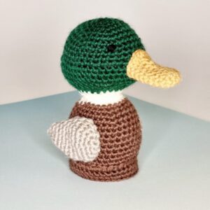 Crocheted mallard duck on white and light blue background