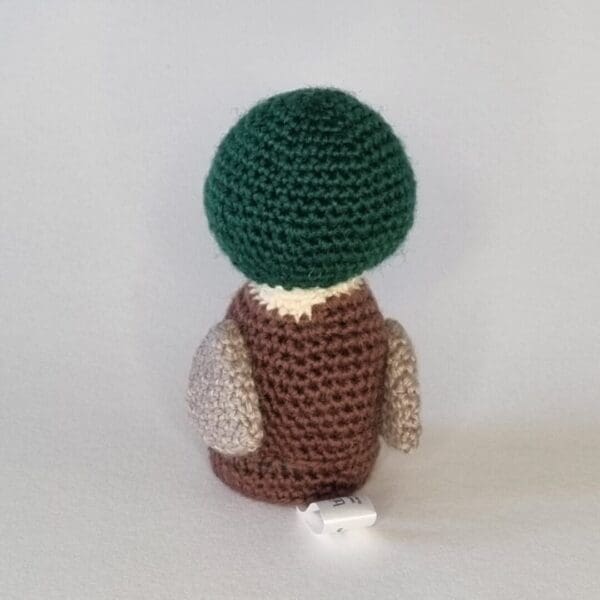 The rear view of a crochet mallard duck on a plain white background