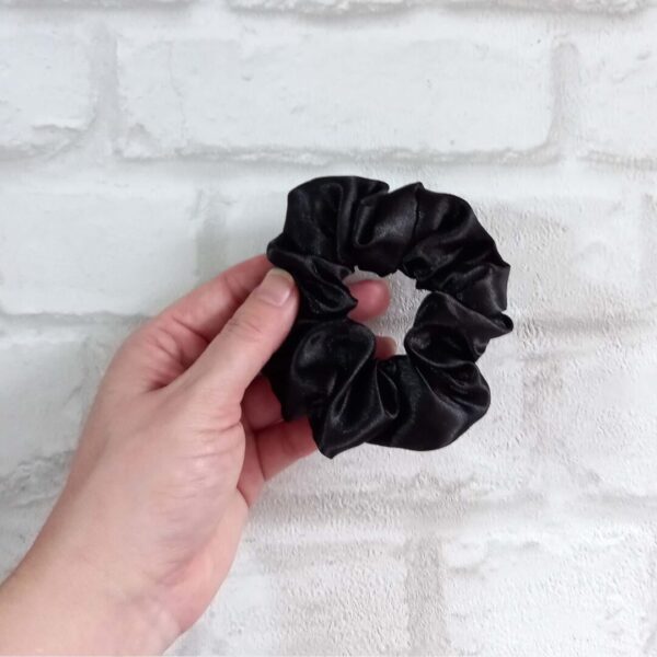 Hand holding a black satin hair scrunchie