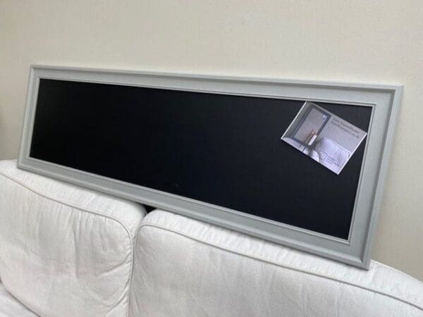 A long magnetic blackboard with ornate frame painted in Farrow & Ball’s Lamp Room Gray