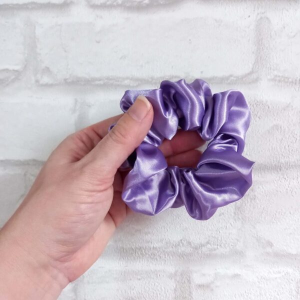 Hand holding lilac satin scrunchie
