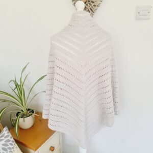 Crochet shawl in white yarn with a hint of silver made by Sarah Lou Crafts. Shown draped over a white mannequin, from the back.