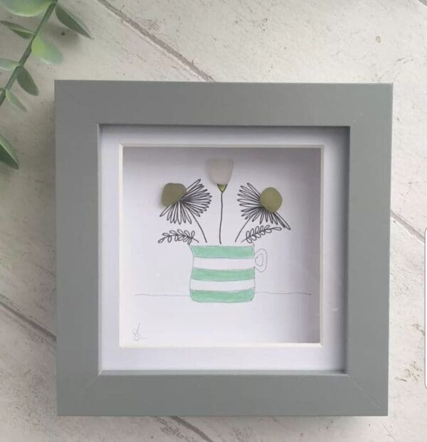 Seaglass flowers in a green and white cornishware inspired jug. Framed in a grey box frame.