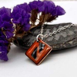 small diamond shaped pendant with orange and blue pattern enamel finish on silver chain