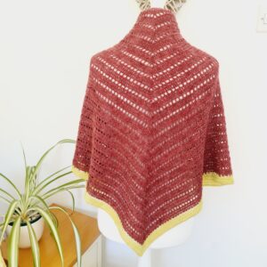 Crochet triangle shawl by Sarah Lou Crafts in a rich red wool, edged with a sunflower yellow border. Shown draped on a white mannequin.