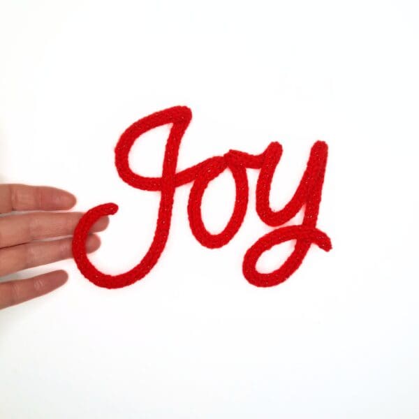 Knitted wire Christmas decoration with the word 'Joy'