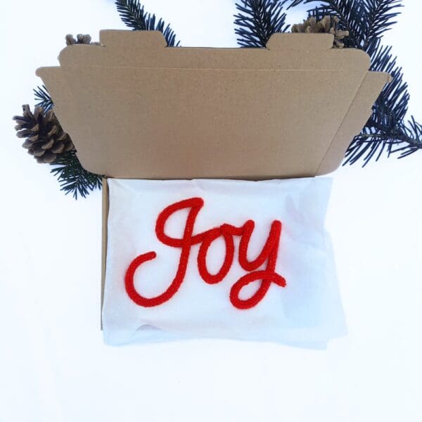 Knitted wire Christmas decoration with the word 'Joy'