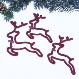 Knitted wire Christmas decoration featuring a leaping reindeer with a tartan bow at its neck.