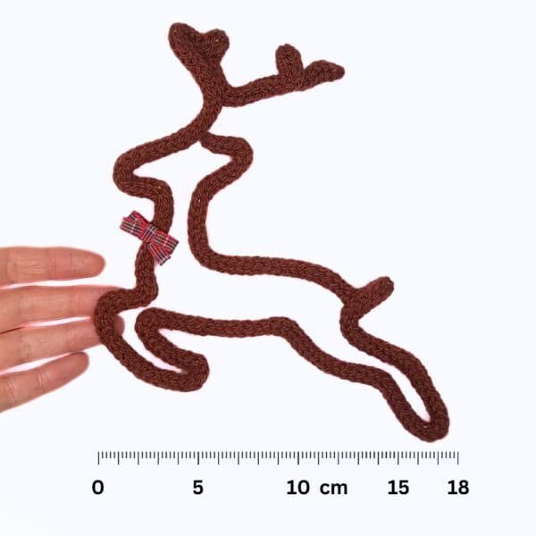 Knitted wire Christmas decoration featuring a leaping reindeer with a tartan bow at its neck.