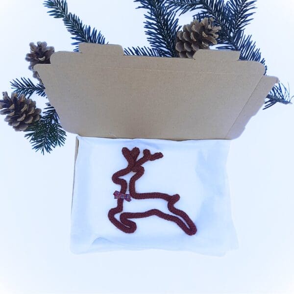 Knitted wire Christmas decoration featuring a leaping reindeer with a tartan bow at its neck.