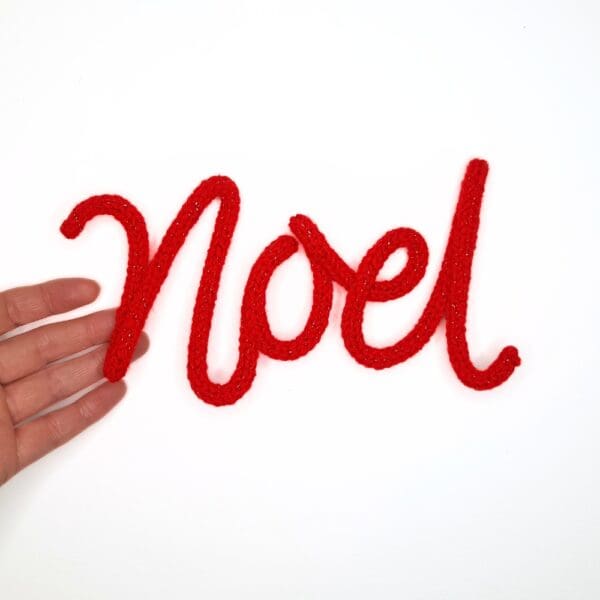 Knitted wire Christmas decoration with the word 'Noel'