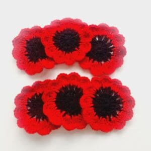 Crochet remembrance poppy coasters set of 6 by Sarah Lou Crafts arranged in a fan of two rows of three on a white table.