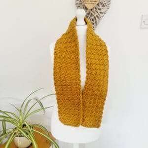 Crochet chunky gold scarf made by Sarah Lou Crafts modelled on white dressmakers dummy.