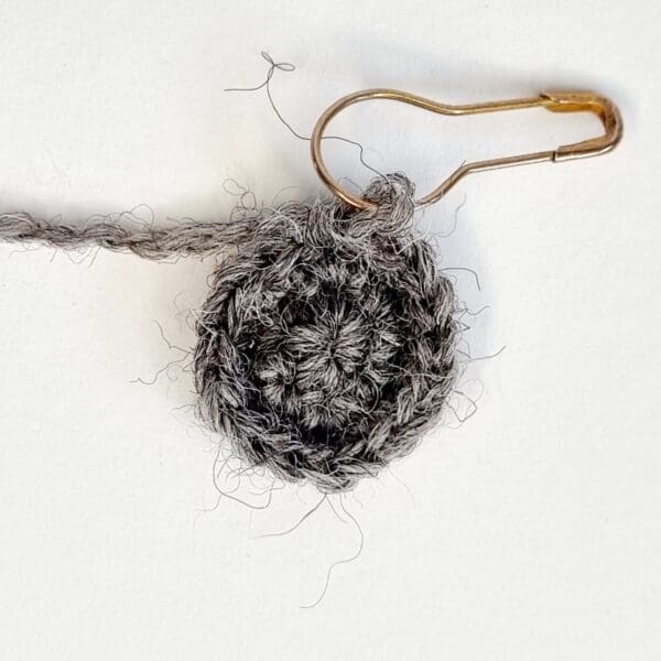 a crochet circle using grey wool with a gold stitch marker