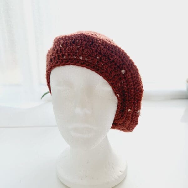 Crochet winter beret hat by Sarah Lou Crafts using an aran yarn called Terracotta. Shown on a white mannequin head.