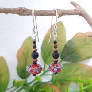 Black and bronze beaded drop earrings with a red Venetian bead at their base and fitted with sterling silver ear hooks.