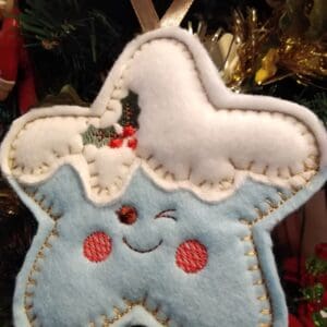 Pale blue felt star with cheeky expression in a festive Christmas theme