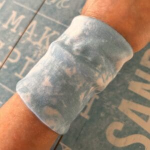 Tie dye look cuff modelled by maker against blue beach theme board