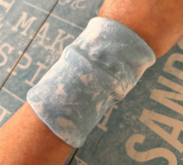 Tie dye look cuff modelled by maker against blue beach theme board