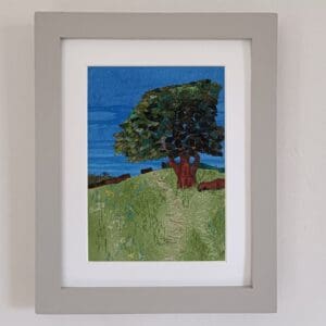 Country scene of hillside meadow in summer with oak tree, all depicted in fabrics with machine stitched details.