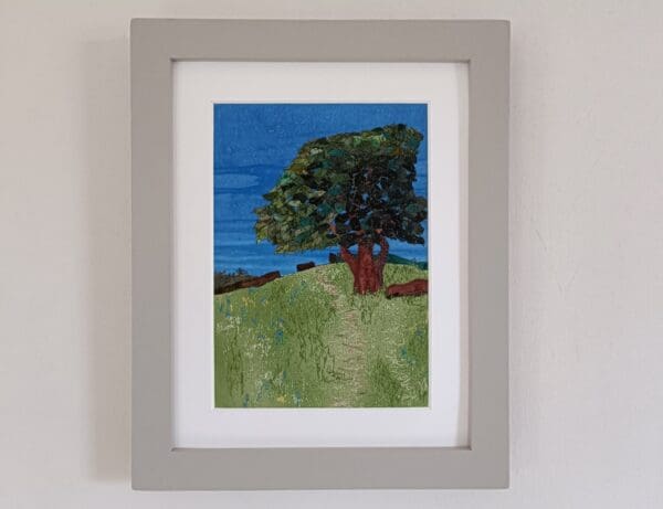 Country scene of hillside meadow in summer with oak tree, all depicted in fabrics with machine stitched details.