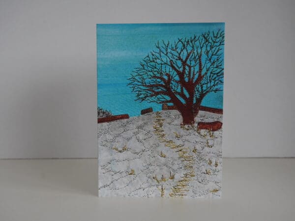 Greetings card of tree in winter on snowy hillside