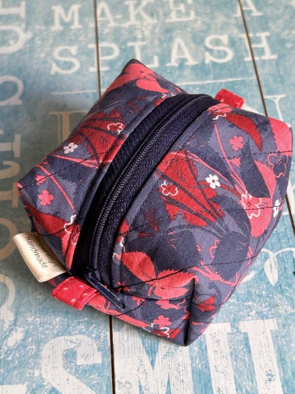 Navy and dark red pouch in box shape displayed against a sky blue background