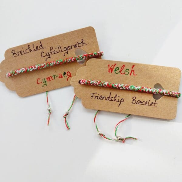 Welsh friendship bracelets shown on brown cards with wording in Welsh, Breichled Cyfeillgarwch Cymraeg. Made by Sarah Lou Crafts