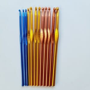 Colourful metal crochet hooks arranged in size order. L-R 3 blue 4mm, 1 gold 4mm, 3 gold 5mm, 4 rose gold 5.5mm and 1 gold 6mm. All laying on a white table with the sizes showing.