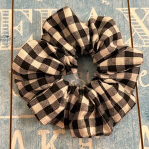 Hair band scrunchie style black and white small gingham against a blue background