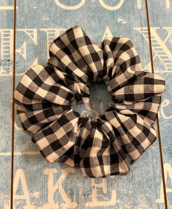 Hair band scrunchie style black and white small gingham against a blue background