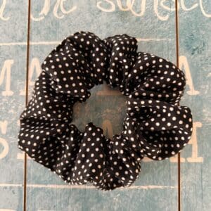 Polka dot black and white fabric hair band against a blue background