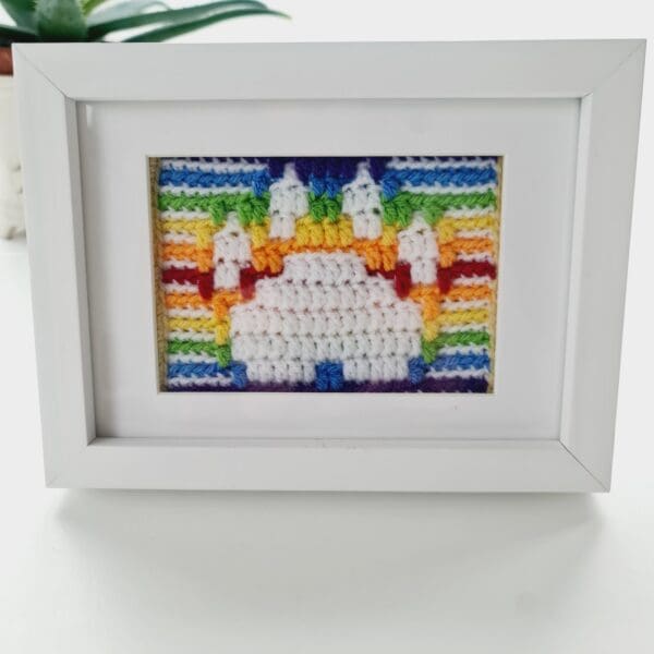 Close up of a paw print picture showing a white paw print with a rainbow stripe background, shown in a white box frame.