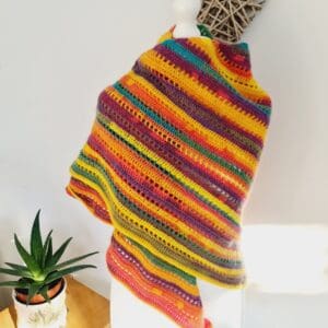 Close-up of a handcrafted crochet triangle scarf by Sarah Lou Crafts, featuring beautiful rainbow of stripes.