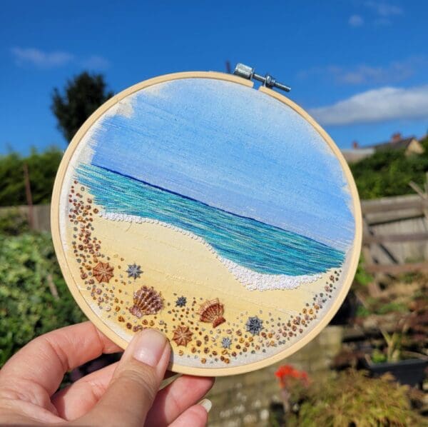 Hand embroidered hoop of shoreline at the beach, showing lots of tiny stnes and shells along the shoreline. 6 inch embroidery hoop ready to hand on the wall.