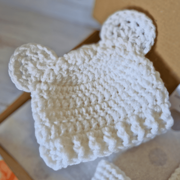 a white handmade crochet teddy bear beanie hat, available in sizes newborn, 0-3 and 3-6 months - making a cute new baby gift