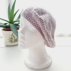Detailed view of the mushroom pink crochet beret's brim. The edge shows a neat, finished crochet stitch, highlighting the craftsmanship from Sarah Lou Crafts. The texture of the yarn is prominent.