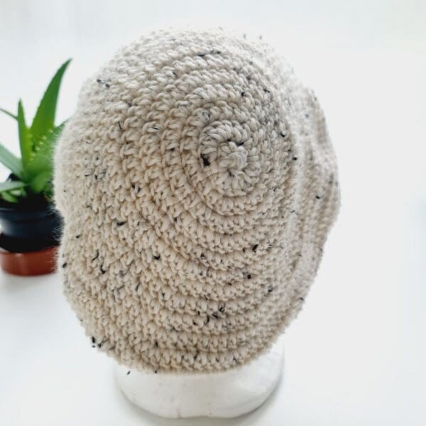 Back view of the cream crochet beret hat by Sarah Lou crafts, emphasizing the gathered crown at the top. The hat's slouchy, relaxed shape is apparent.