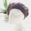 Side view of the grape coloured crochet beret hat by Sarah Lou crafts, emphasizing the hat's slouchy, relaxed shape is apparent.