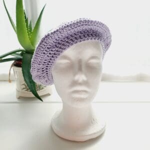 Detailed view of the lilac cotton crochet beret. The edge shows a neat, finished crochet stitch, highlighting the craftsmanship from Sarah Lou Crafts. The texture of the yarn is prominent.