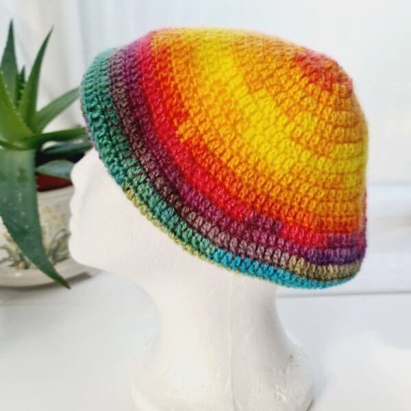 Side view of the rainbow crochet beret hat by Sarah Lou crafts, emphasizing the gathered crown at the top. The hat's slouchy, relaxed shape is apparent.