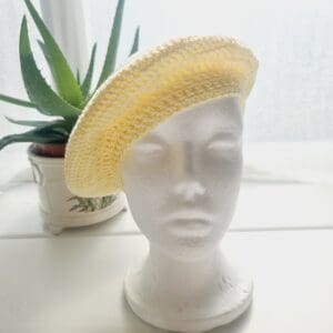 Detailed view of the yellow cotton crochet beret. The edge shows a neat, finished crochet stitch, highlighting the craftsmanship from Sarah Lou Crafts. The texture of the yarn is prominent.