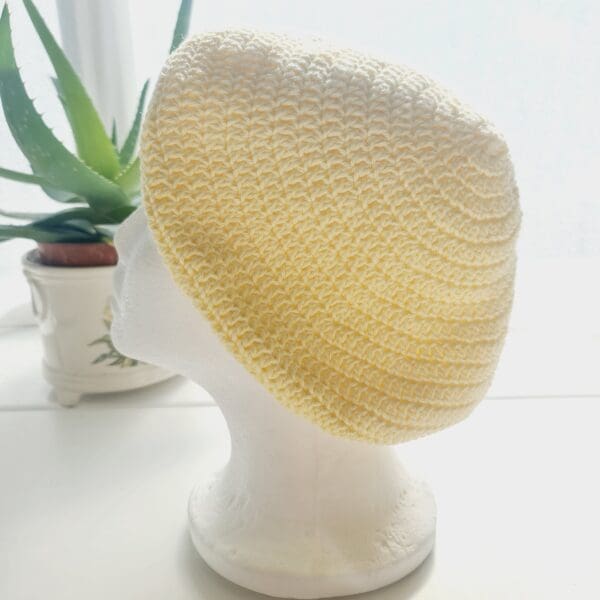 Side view of the yellow cotton crochet beret hat by Sarah Lou crafts, emphasizing the gathered crown at the top. The hat's slouchy, relaxed shape is apparent.