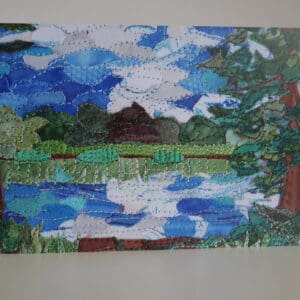 Print of textile collage showing a pond with trees around it and blue sky reflected in it along with clouds.